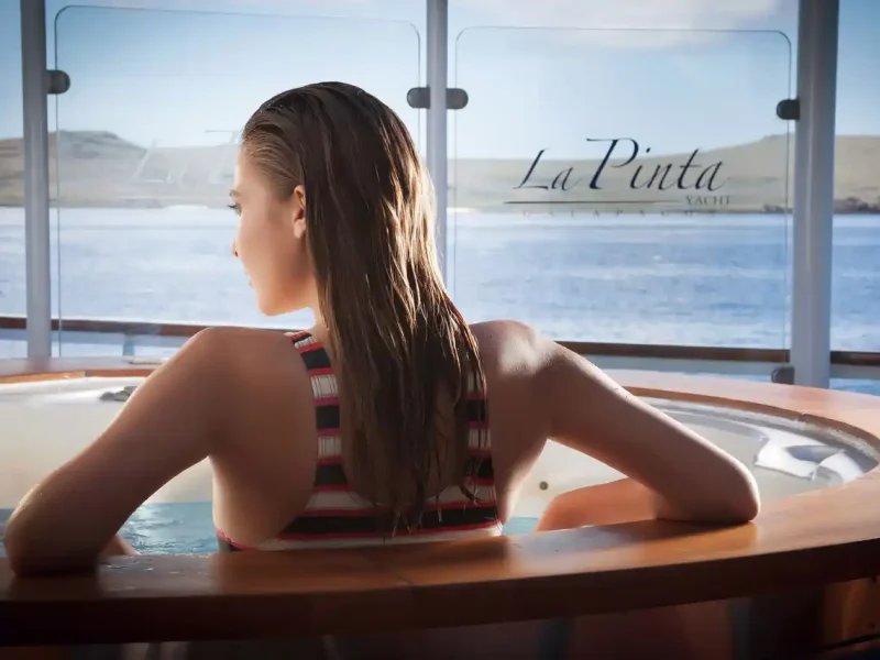 A guest relaxing in the Sun Deck hot tub aboard La Pinta with island views