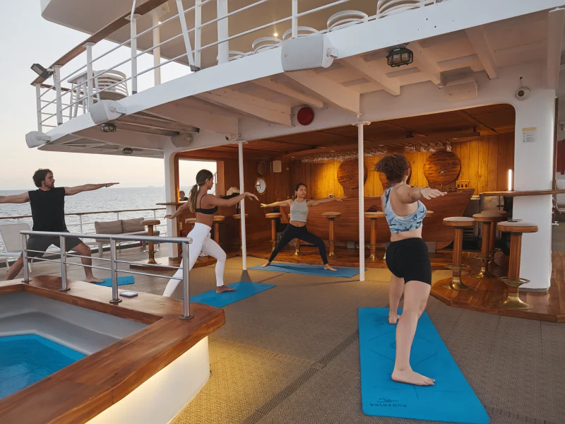 Guests practicing yoga on the sun deck aboard Galápagos Legend